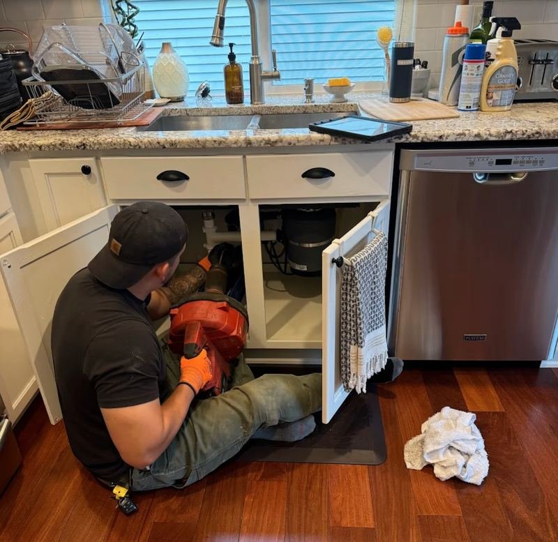 Plumber clearing a blocked kitchen line with a sectional drain machine